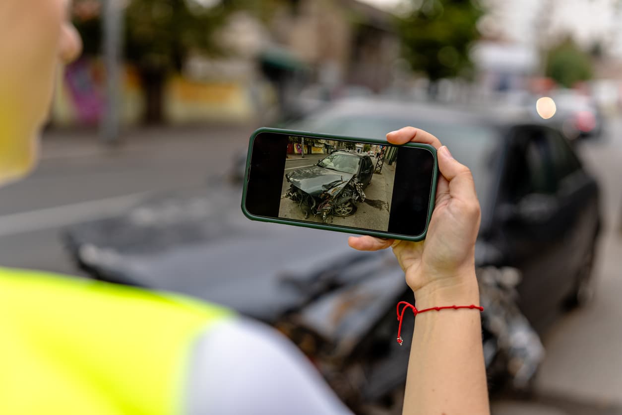 A person photographing a car accident scene, capturing details for documentation and reporting purposes in Illinois.