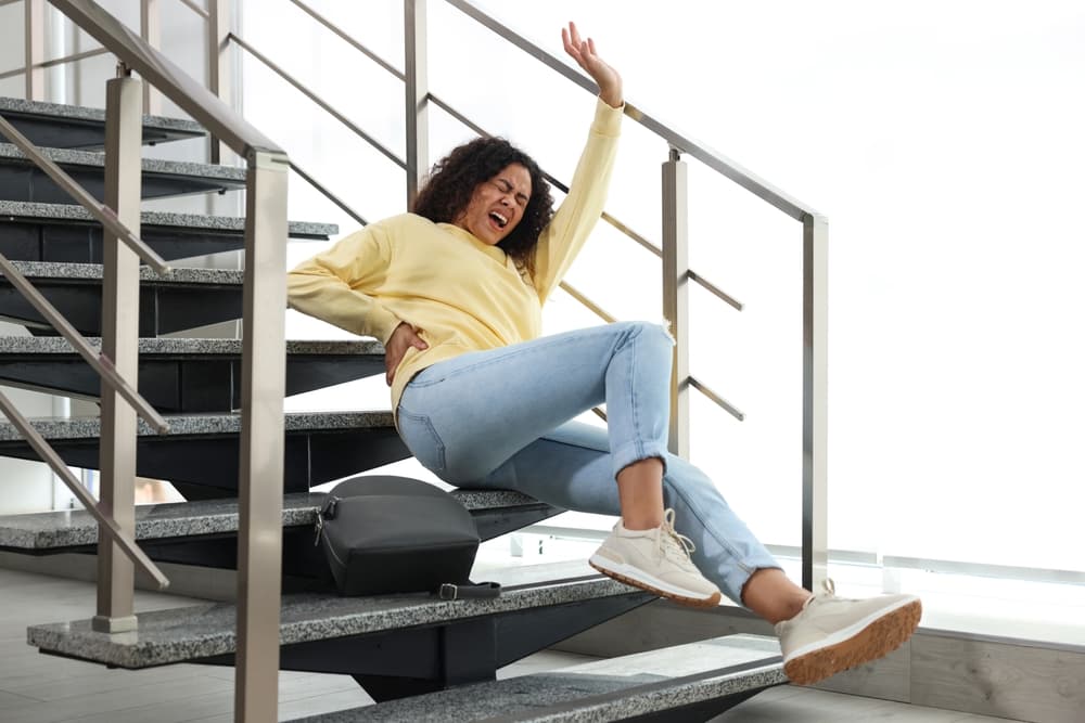 A woman sitting on stairs with her arms raised, depicting a slip-and-fall incident in Wisconsin.
